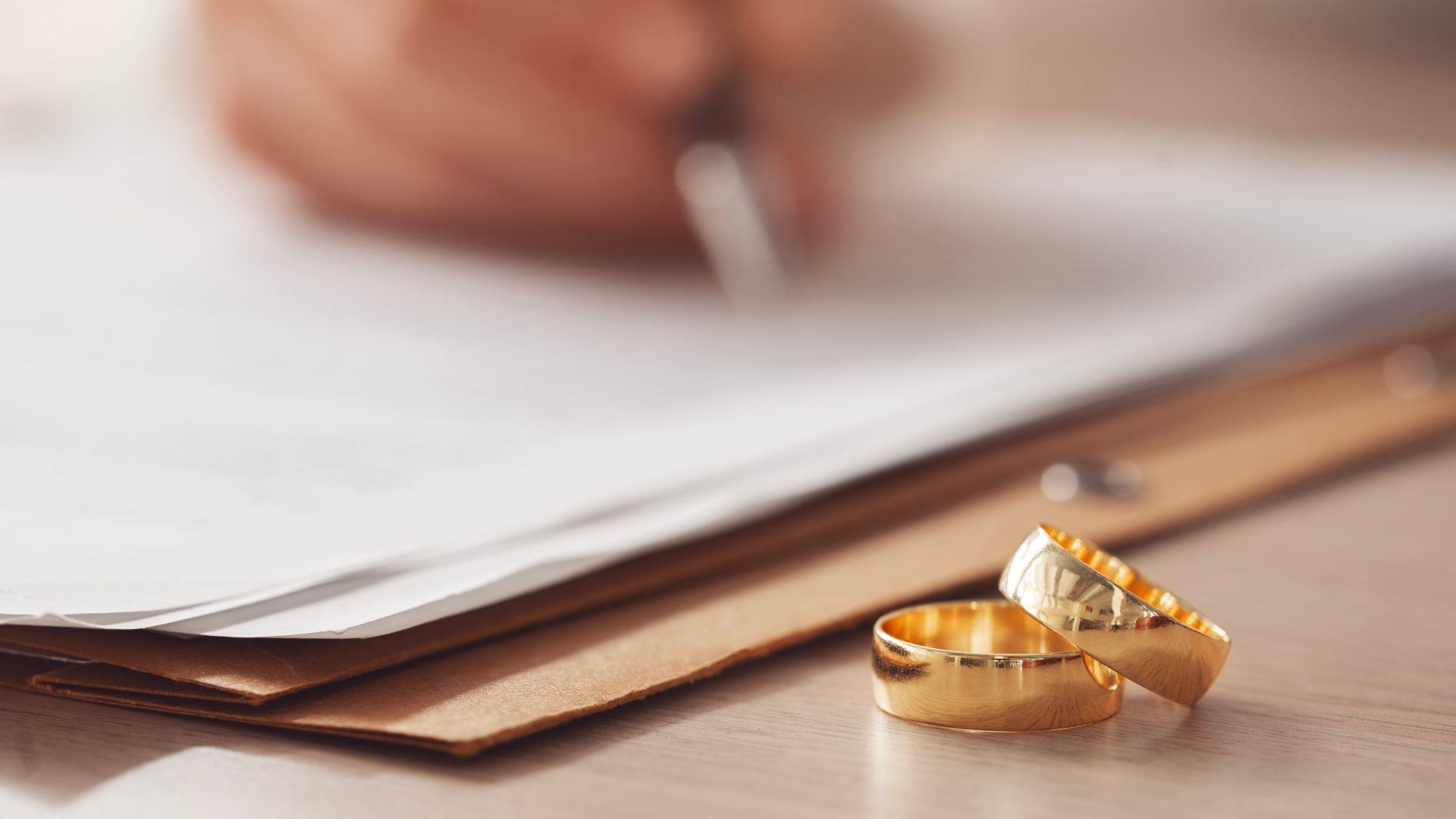 Symbolfoto: Ringe neben Dokument – Regelungen zu Güterstand & Unterhalt