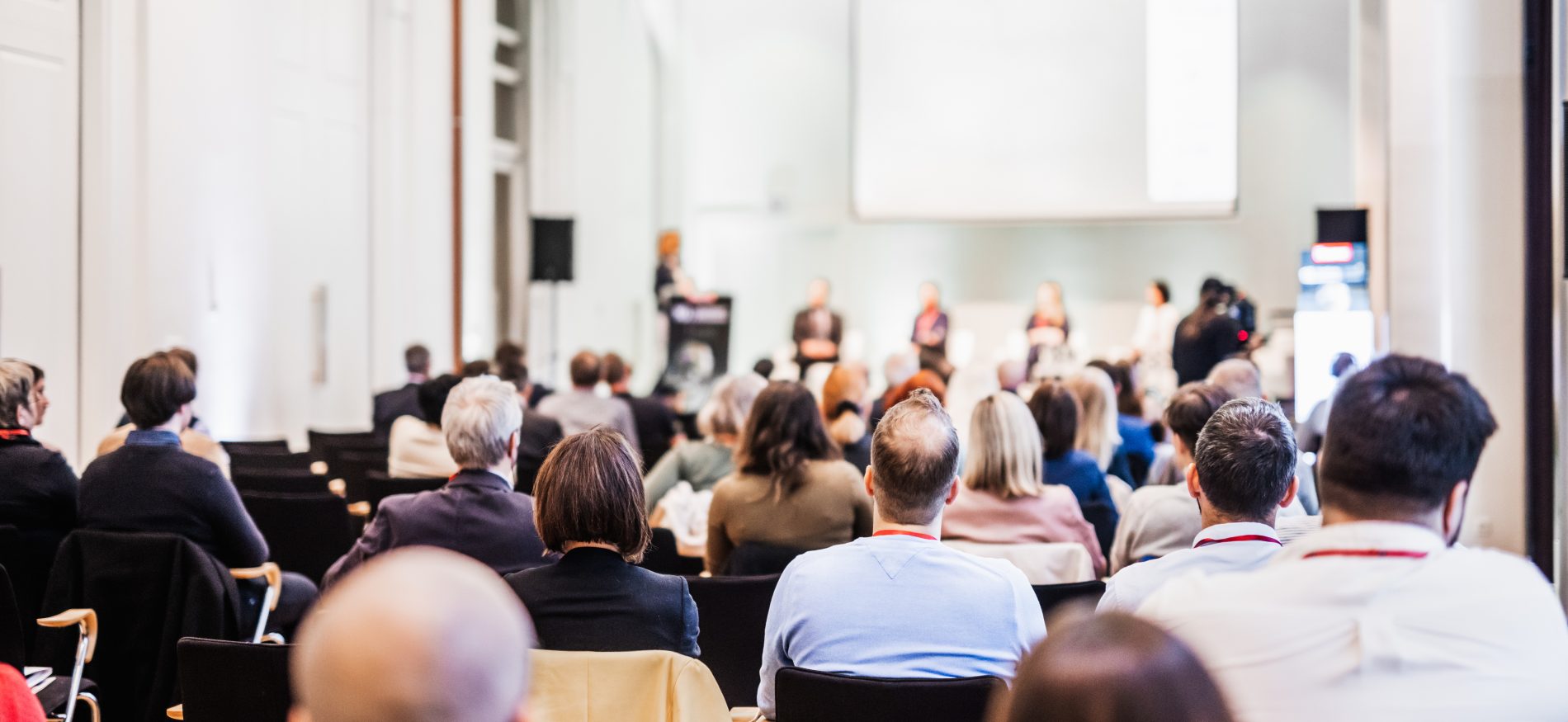 Menschen sitzen in einem Konferenzsaal und hören einer Podiumsdiskussion zu